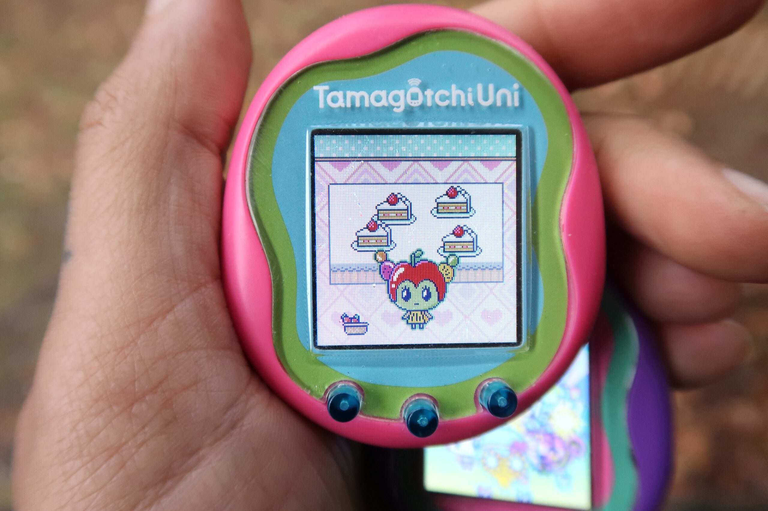 Pink Tamagotchi Uni pictured in a hand displaying the new character Tanghulutchi