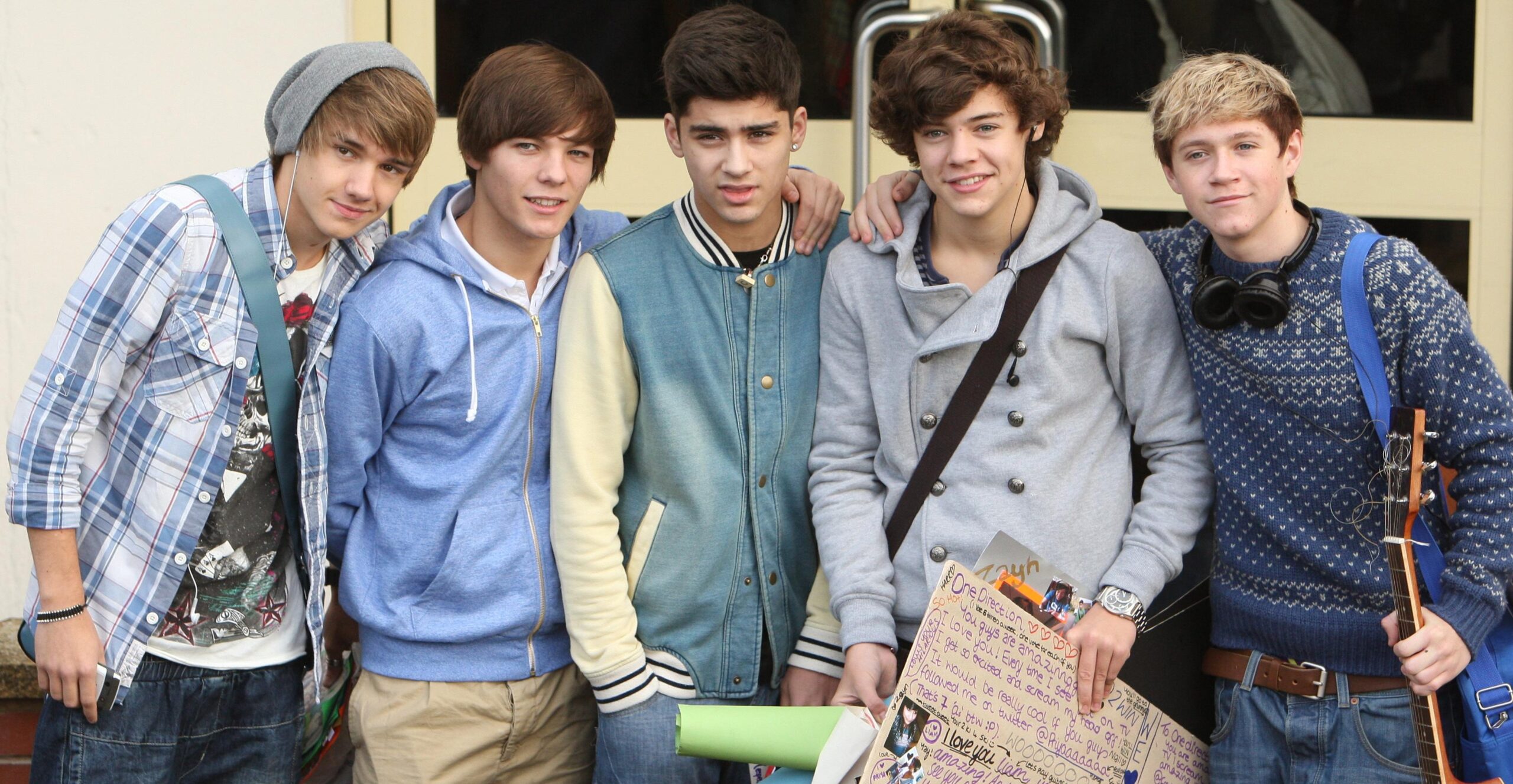 Five young men, one holding a guitar.