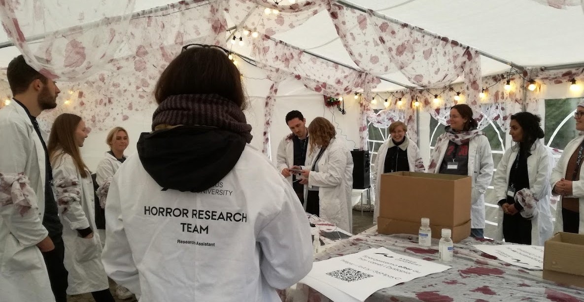 Team members with white coats stand in a decorated tent.