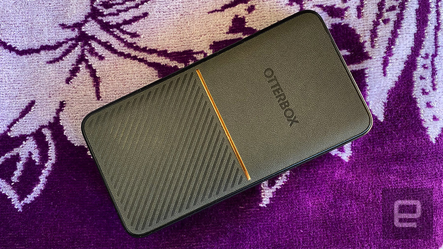 The OtterBox Fast Charge Power Bank portable battery rests on a purple floral towel. 