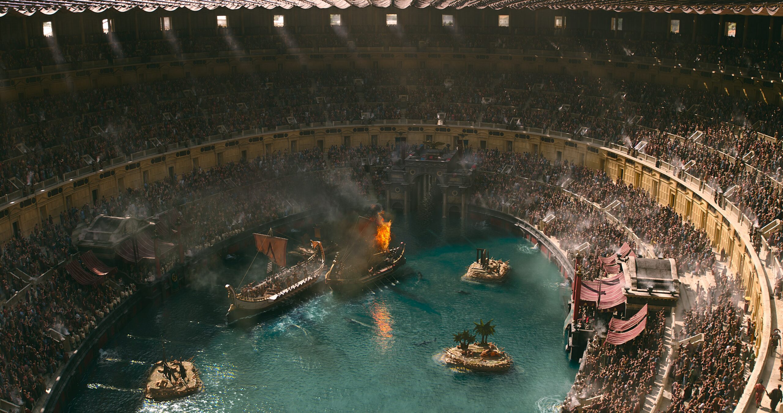 The Roman Colosseum full of spectators watching a mock naval battle taking place in the flooded center.