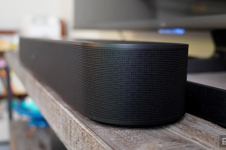 The sonos beam soundbar sits on a wooden shelf next to a TV