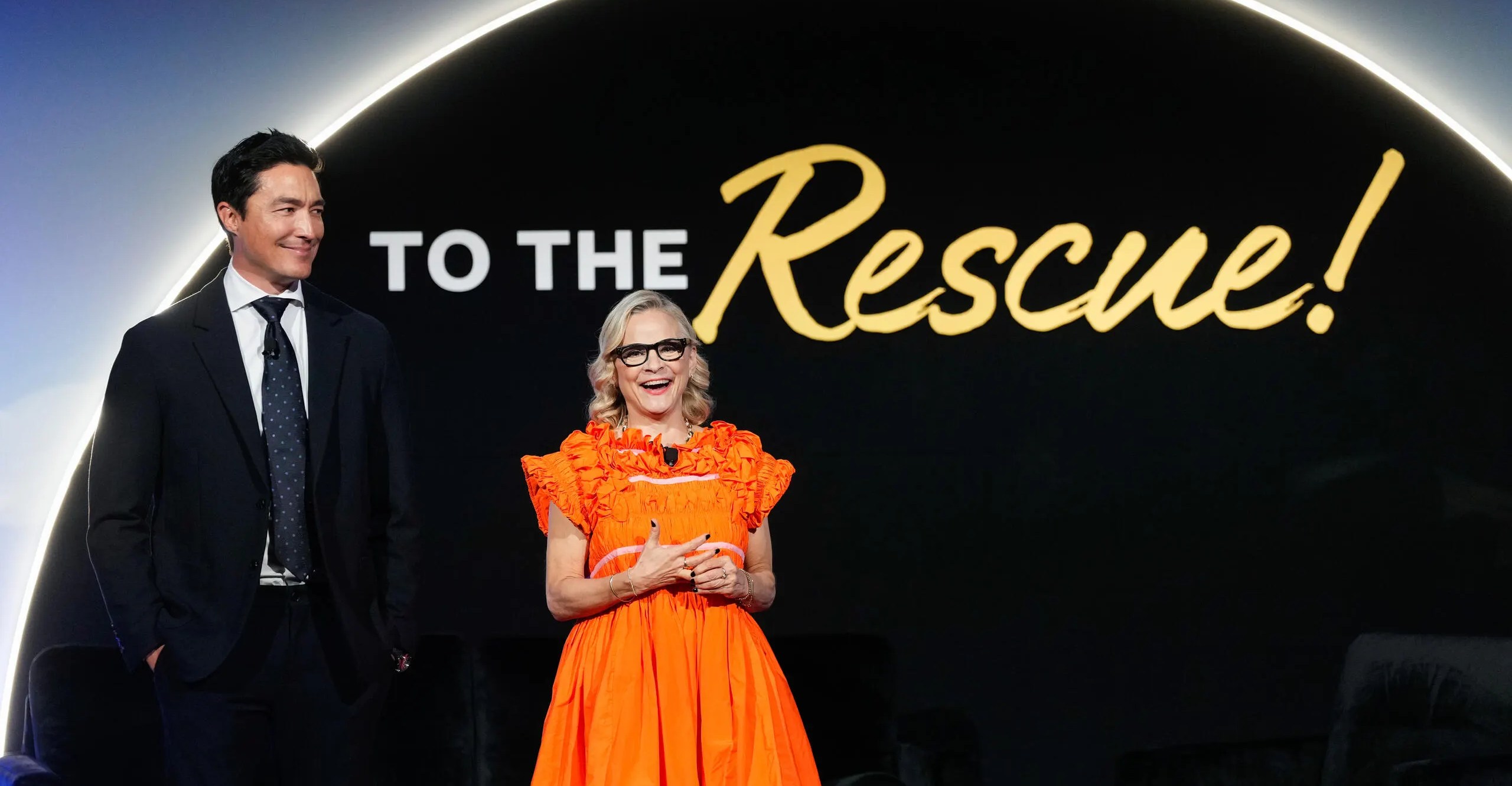 Amy Sedaris on stage at the Humane Society gala wearing an orange dress with ruffles around the shoulders