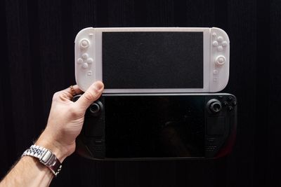 A white, 3D-printed mockup of a Nintendo Switch 2 held in a hand above Valve’s Steam Deck.