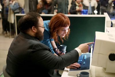 A photo of Zach Cherry and Britt Lower using a Lumon computer at an installation at Grand Central Station in New York.