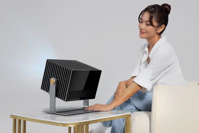 A persion positions the Valerion VisionMaster Max projector sitting on a small side table.