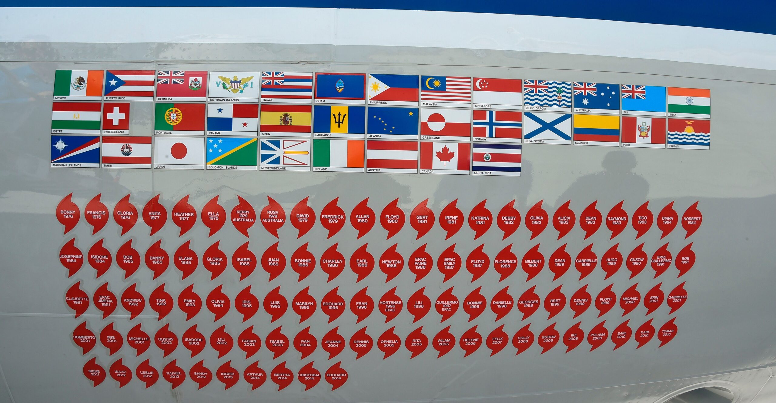 The nose of one of NOAA’s hurricane hunter aircraft displays long rows of stickers, around 100 of them in lines.