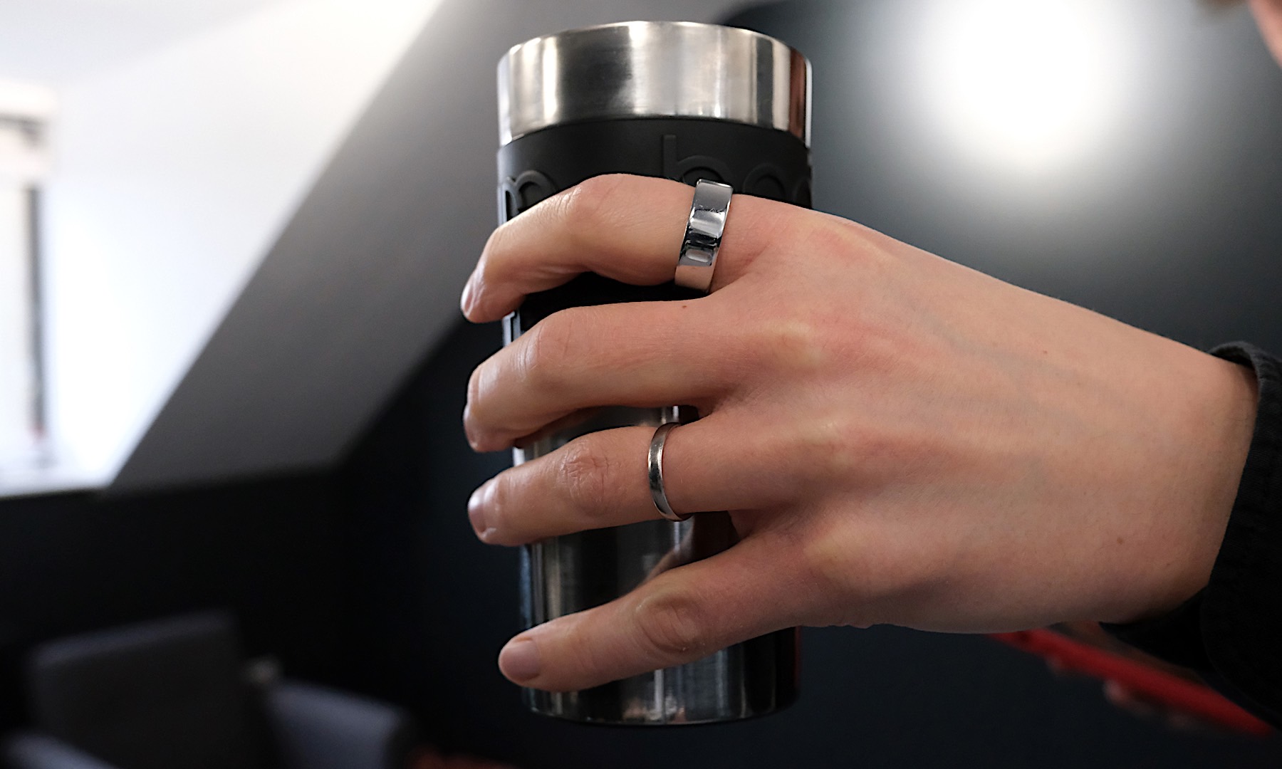 Image of a hand wearing an Oura Ring while holding a Bodum travel mug, which adds a nice offset for the color.