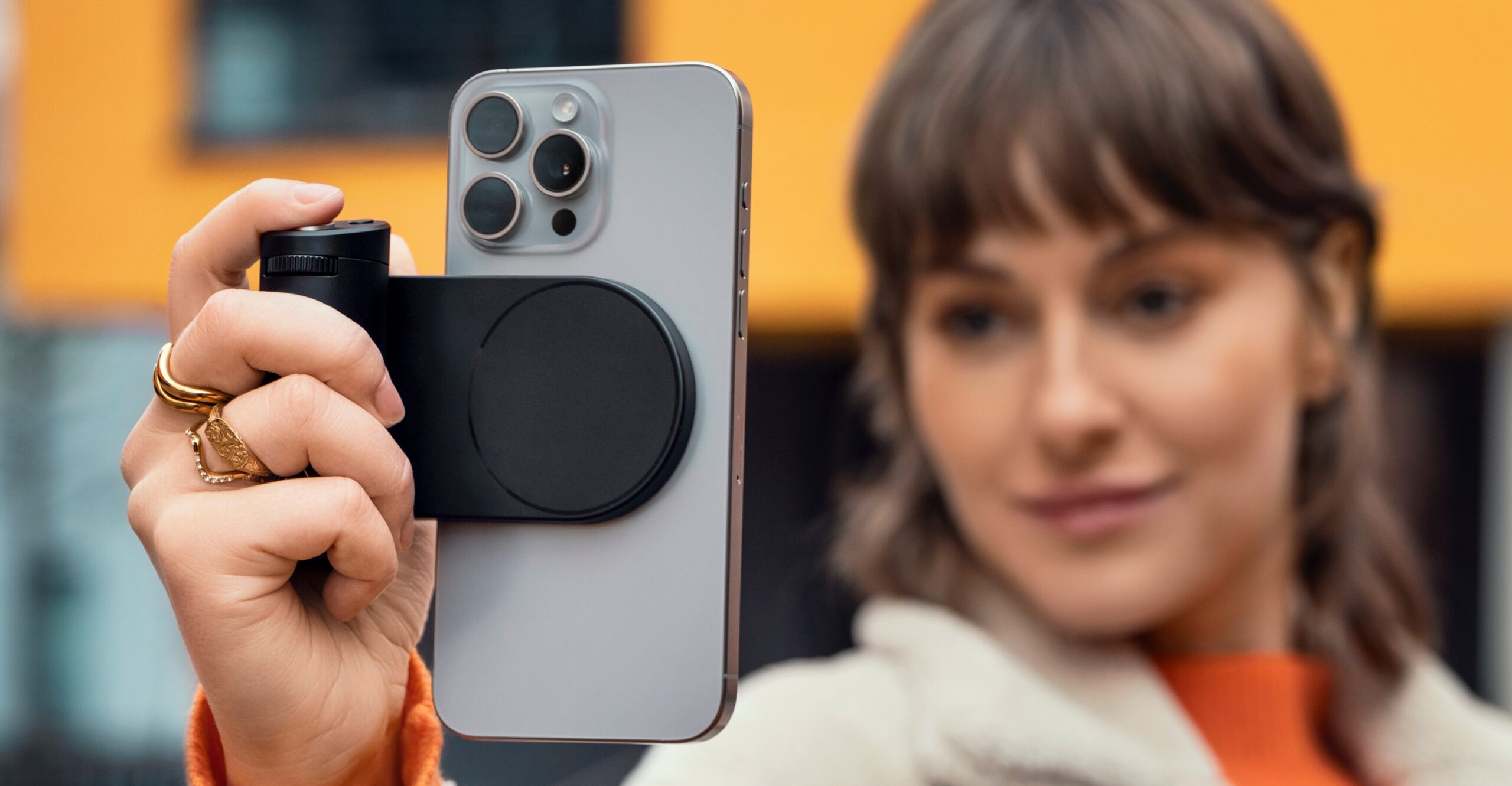 A person holding the Leica Lux Grip while it’s attached to an iPhone held vertically.