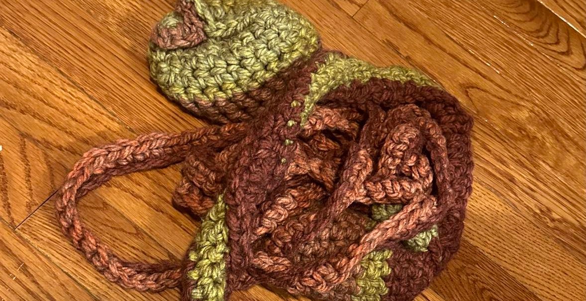 A tangled crochet replica of a macaque’s gastrointestinal tract, made of pink, brown, and green yarn. 