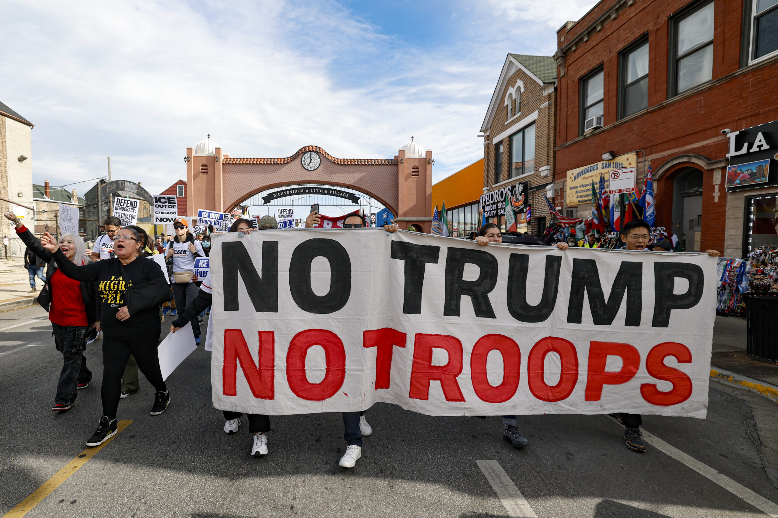 Protesters in Chicago march down the Mexican American neighborhood with a sign that reads No Trump No Troops