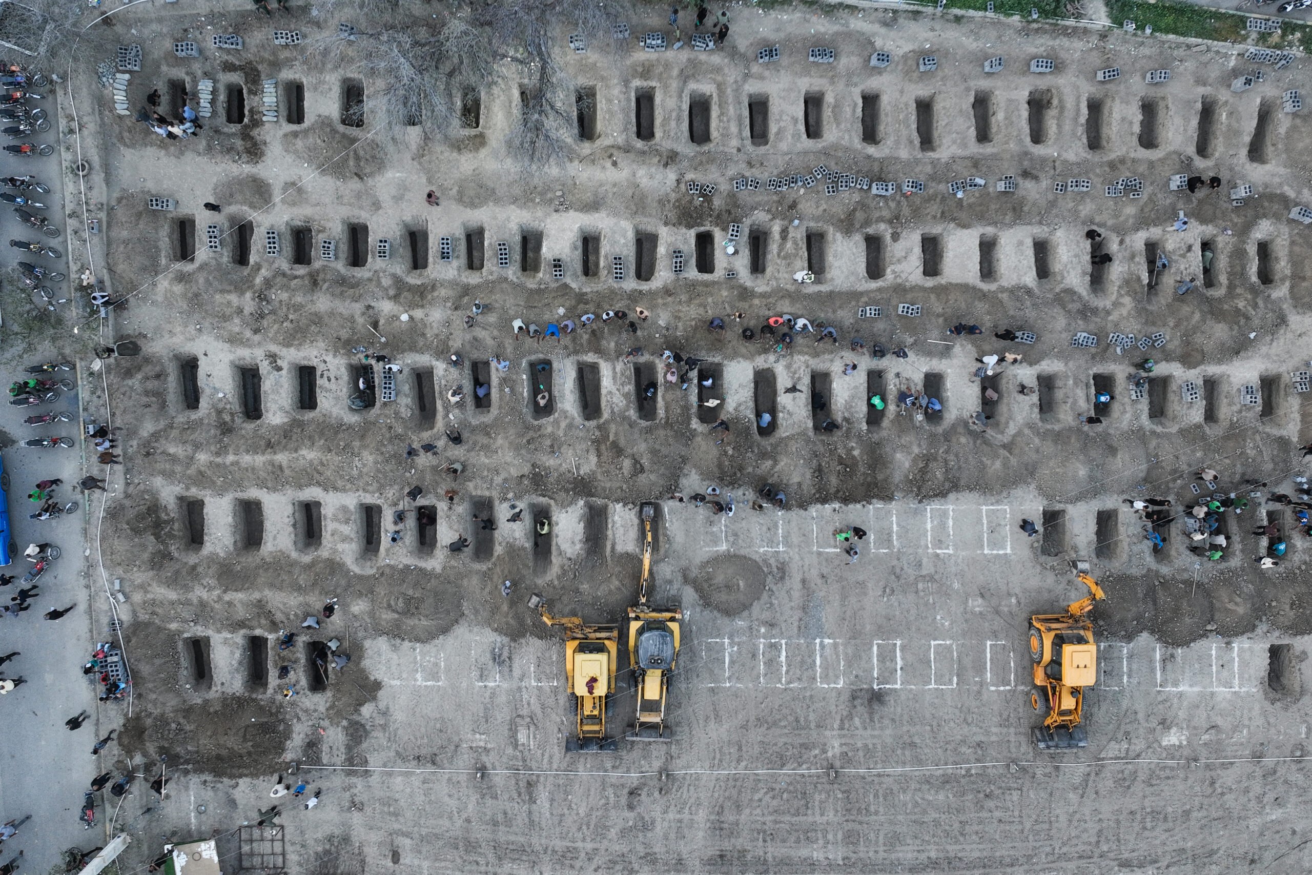 Aerial image of mourners digging graves during a funeral for children killed in a reported strike
