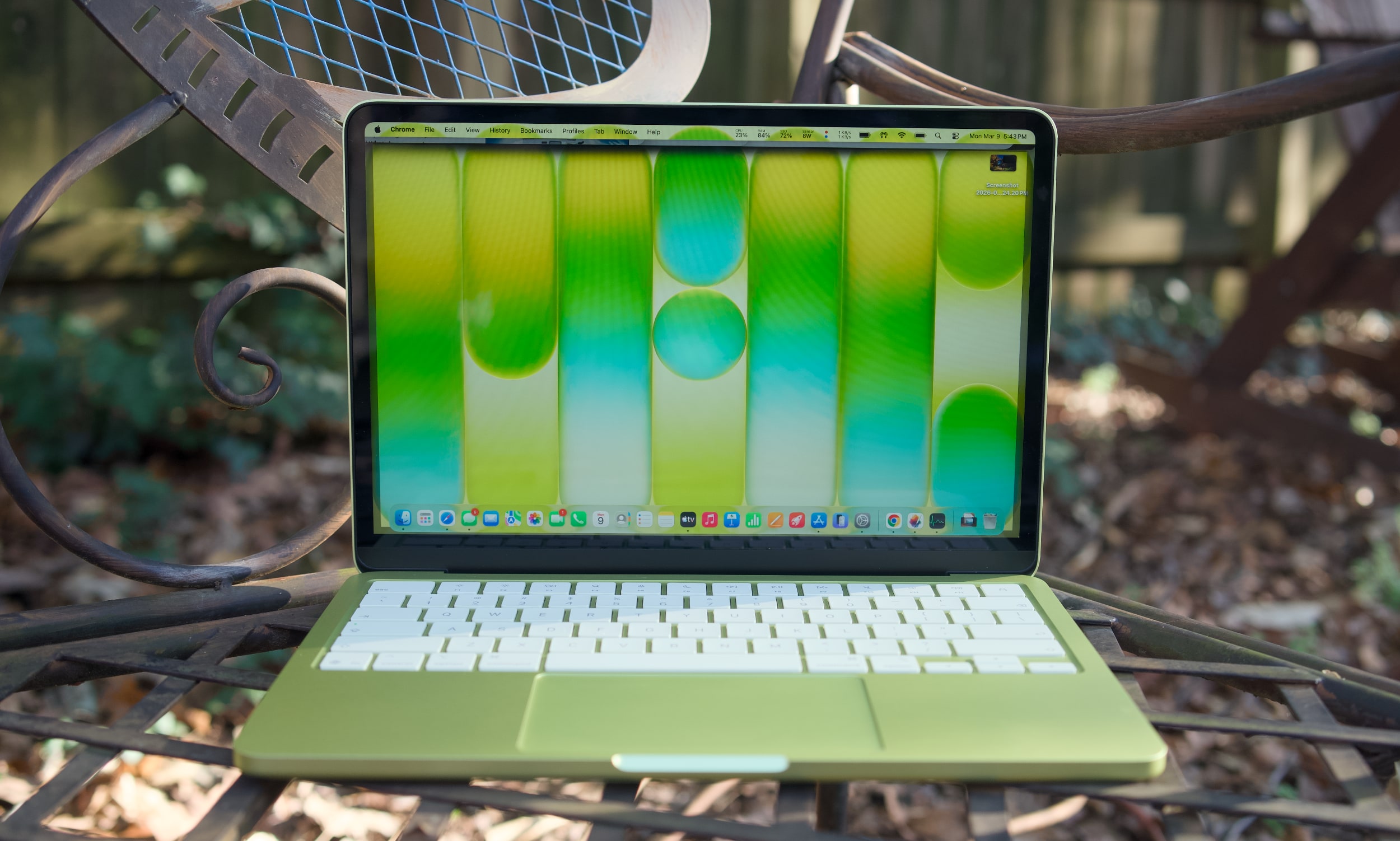 A citrus MacBook Neo on a table outside.