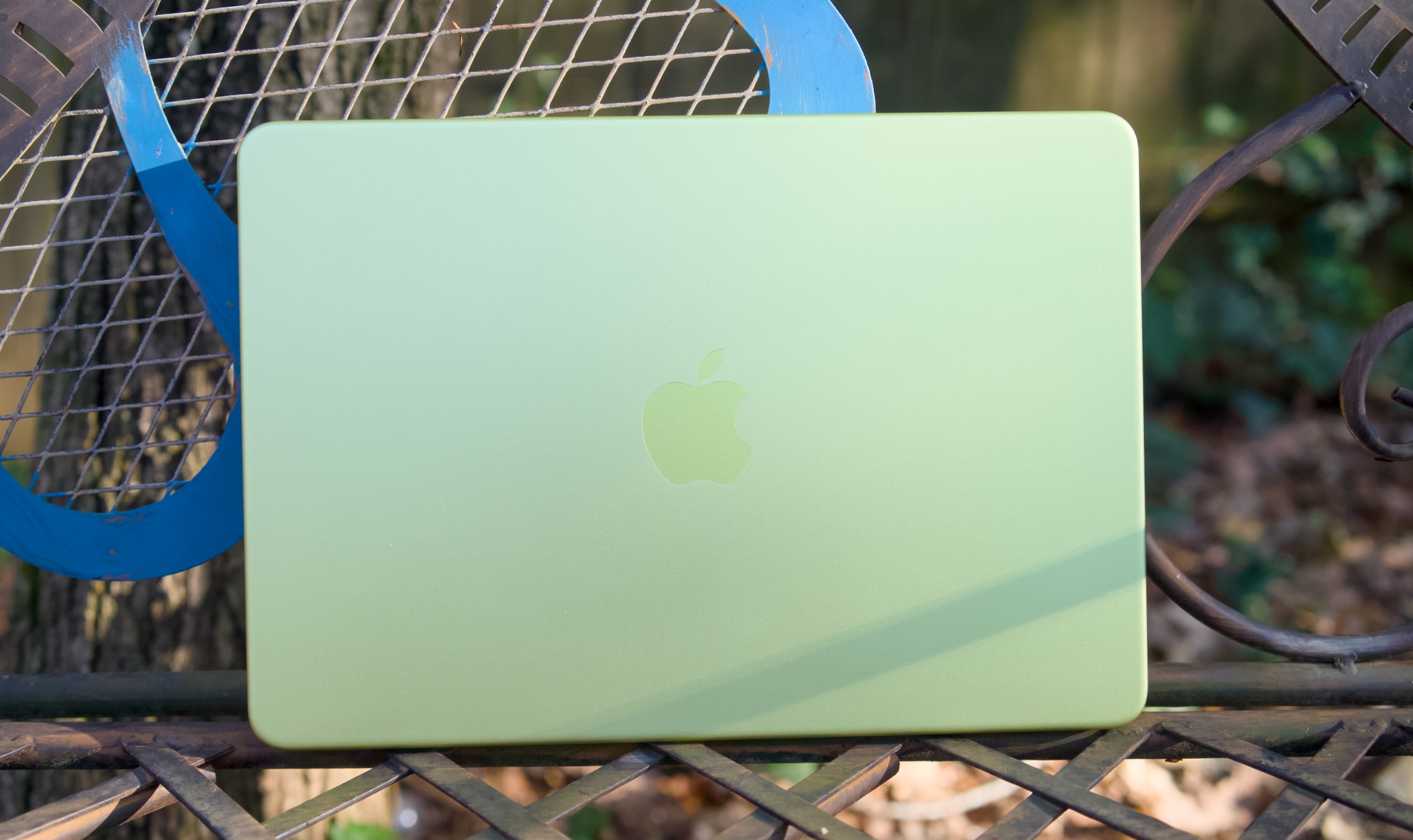 A citrus MacBook Neo on a table outside.