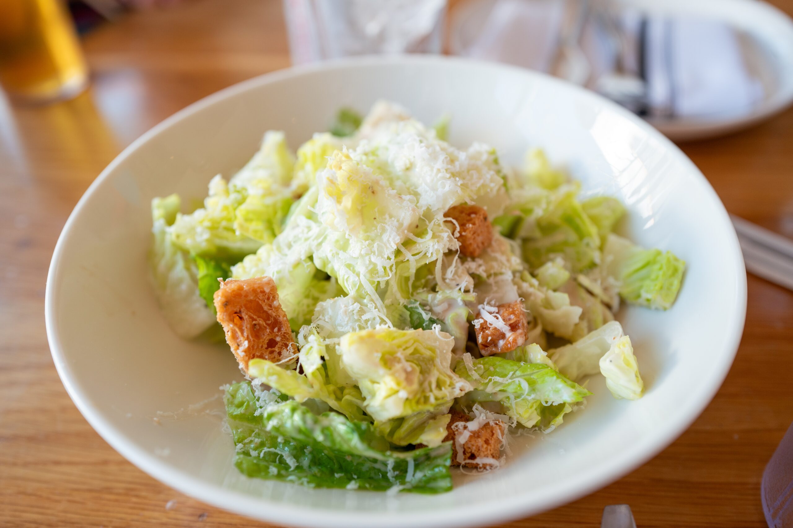 Caesar salad with Parm and croutons on a white plate