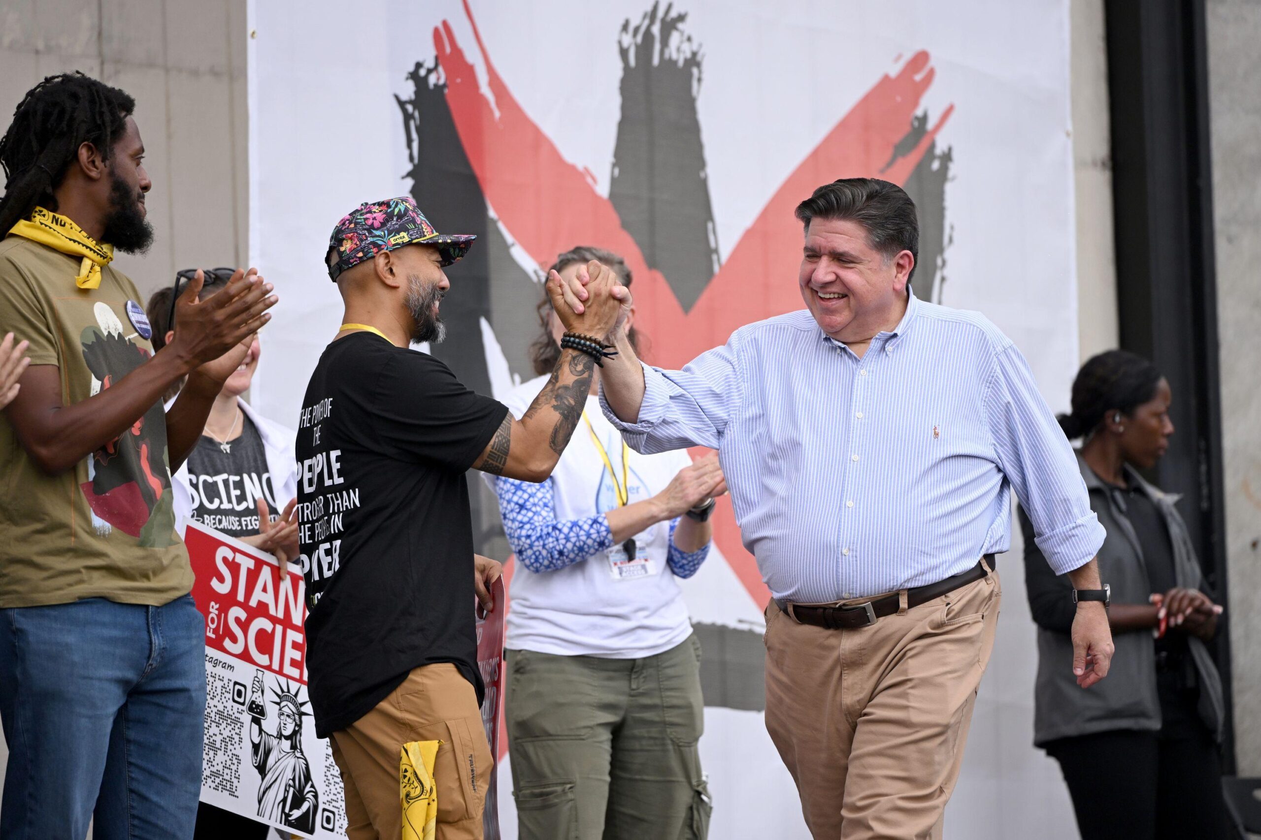 JB Pritzker giving a high-five to a person onstage