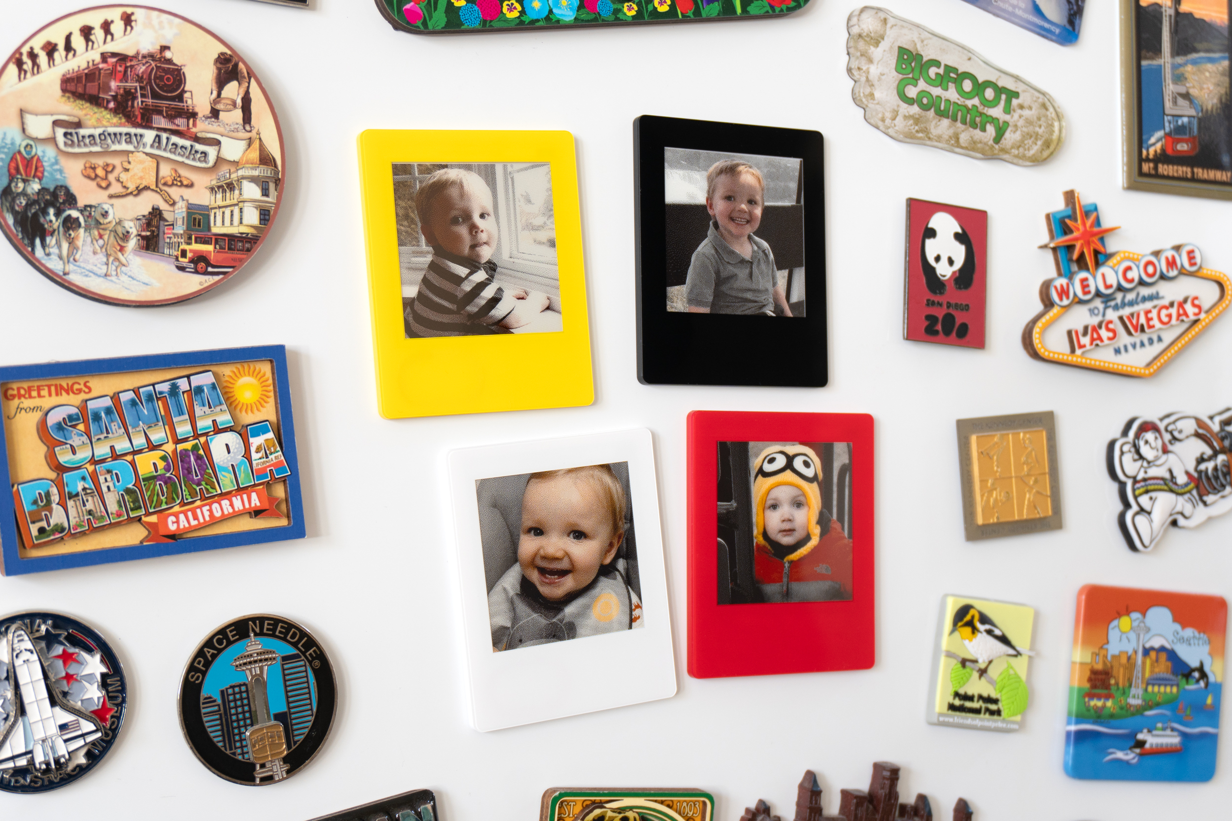 Four VidaBay Snap magnetic photo frames attached to a white board surrounded by magnets.