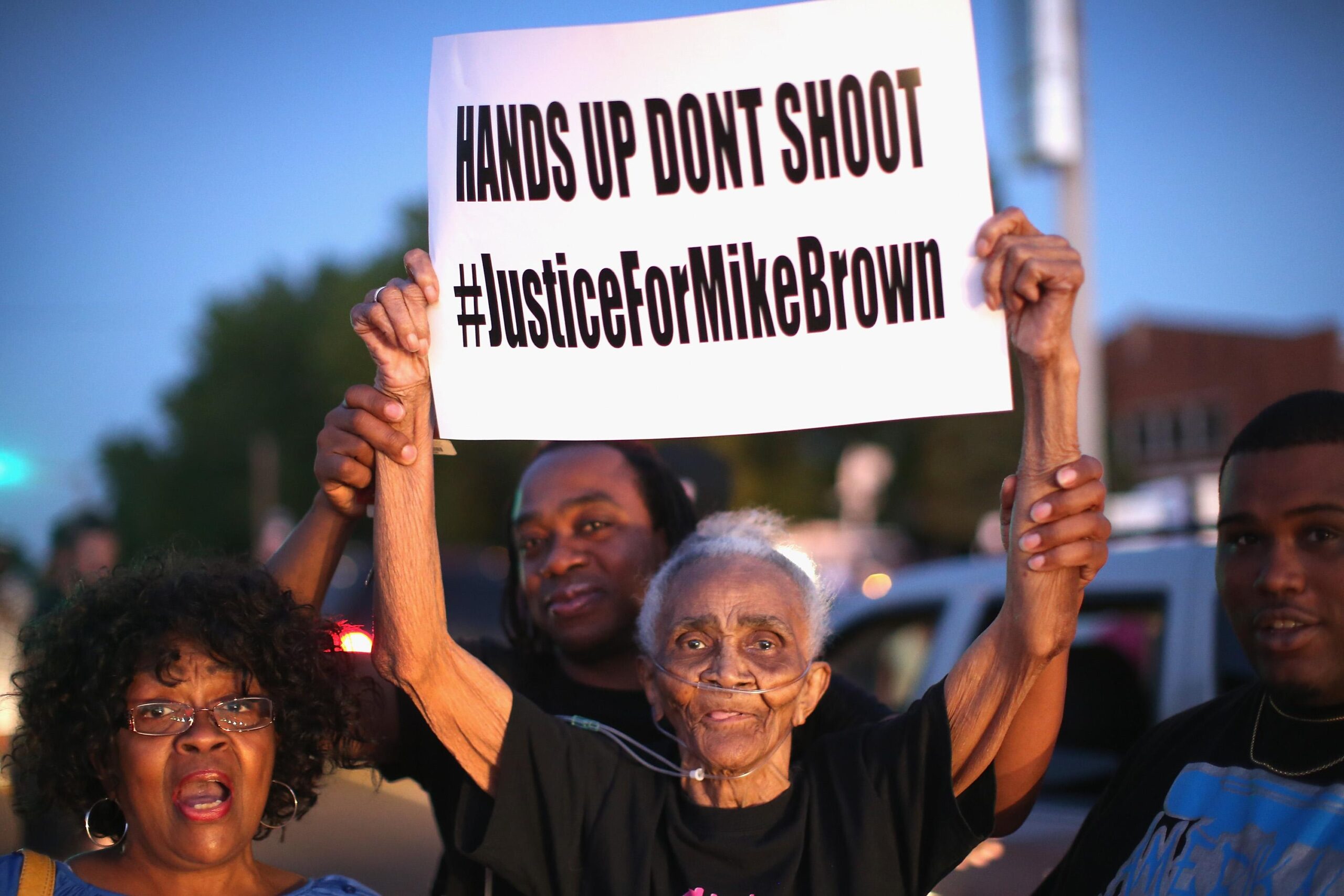 An 88yearold woman holds up a protest sign that says hands up don’t shoot
