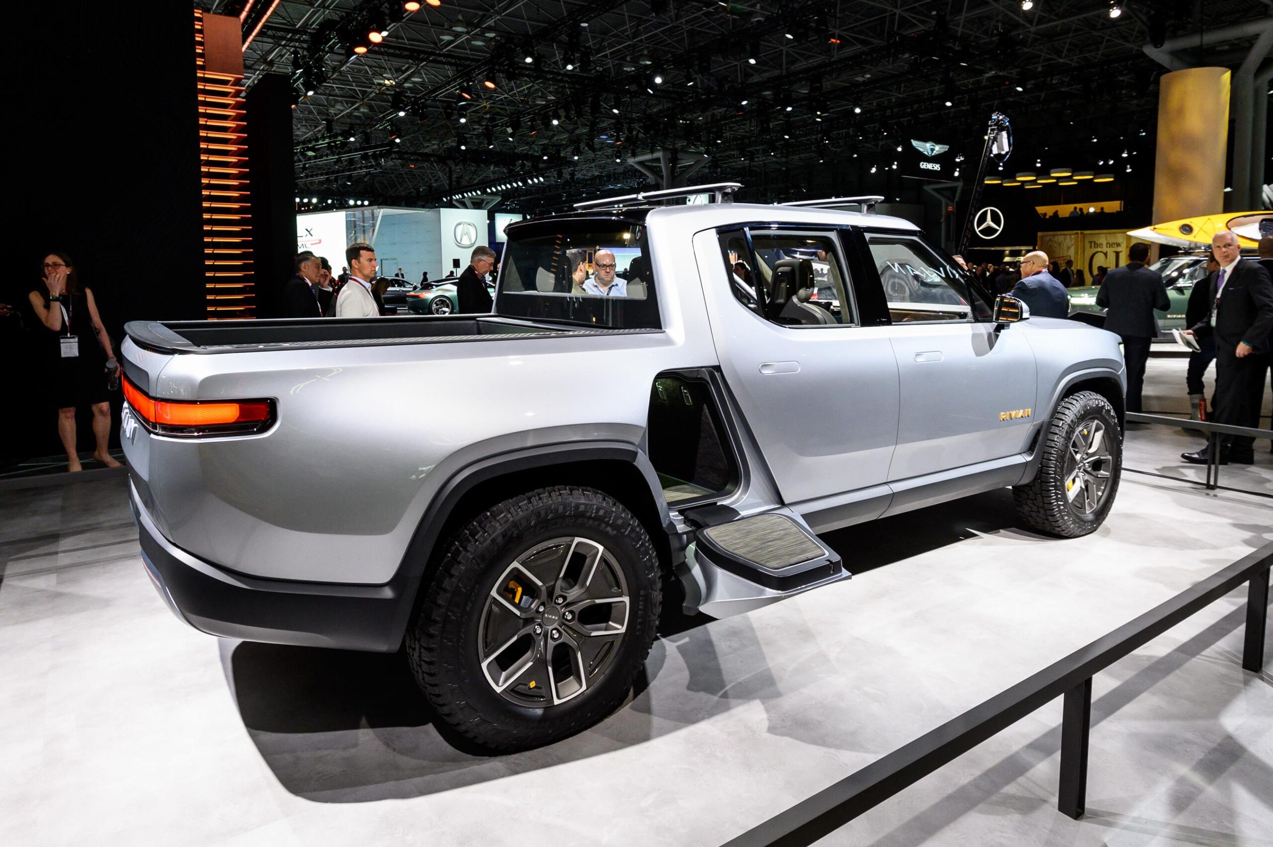 A silver Rivian R1T is on display with the door to the "Rivian Gear Tunnel" open. A silver Rivian R1T is on display with the door to the "Rivian Gear Tunnel" open.
