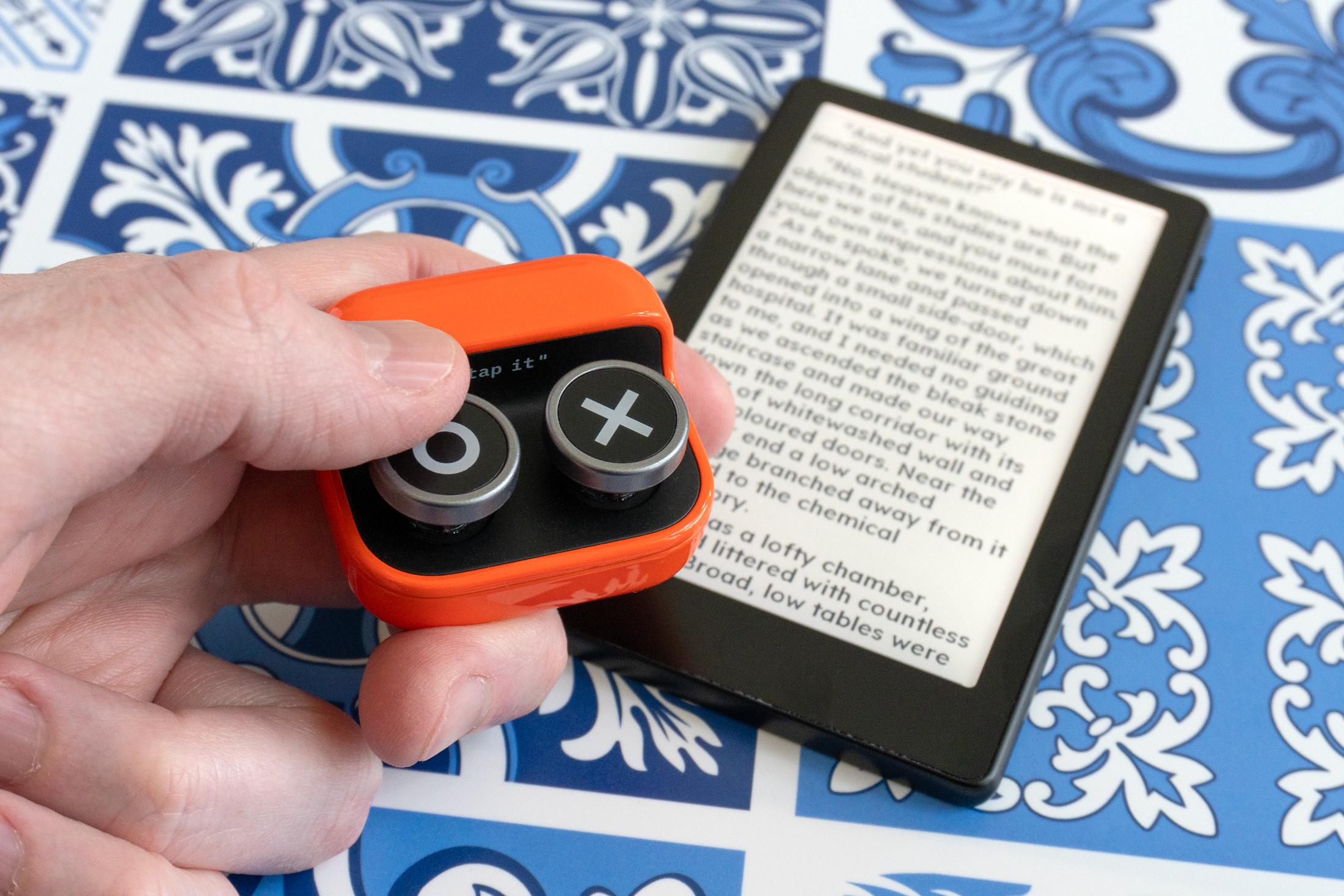A person holding the Boox Tappy remote above the Xteink X4 Pro. A person holding the Boox Tappy remote above the Xteink X4 Pro.
