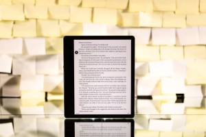 The Kindle Paperwhite standing upright in front of a background of yellow post-it notes.