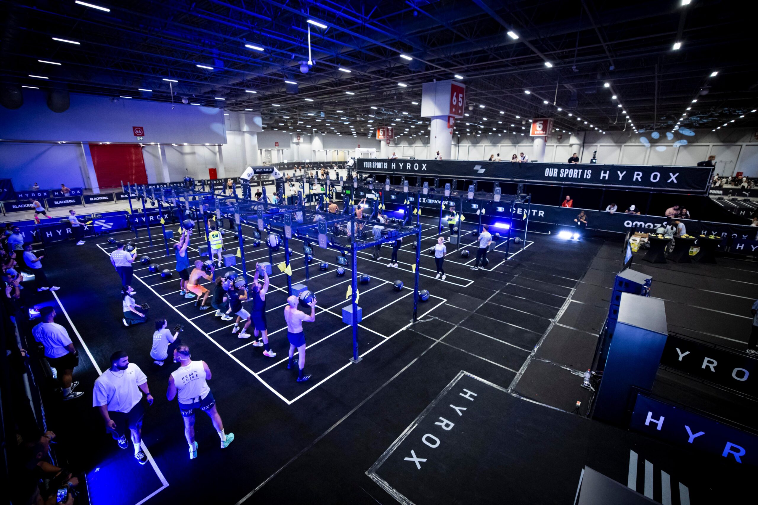 People in front of exercise stations in the gym about to perform a weighted or strength-based exercise.