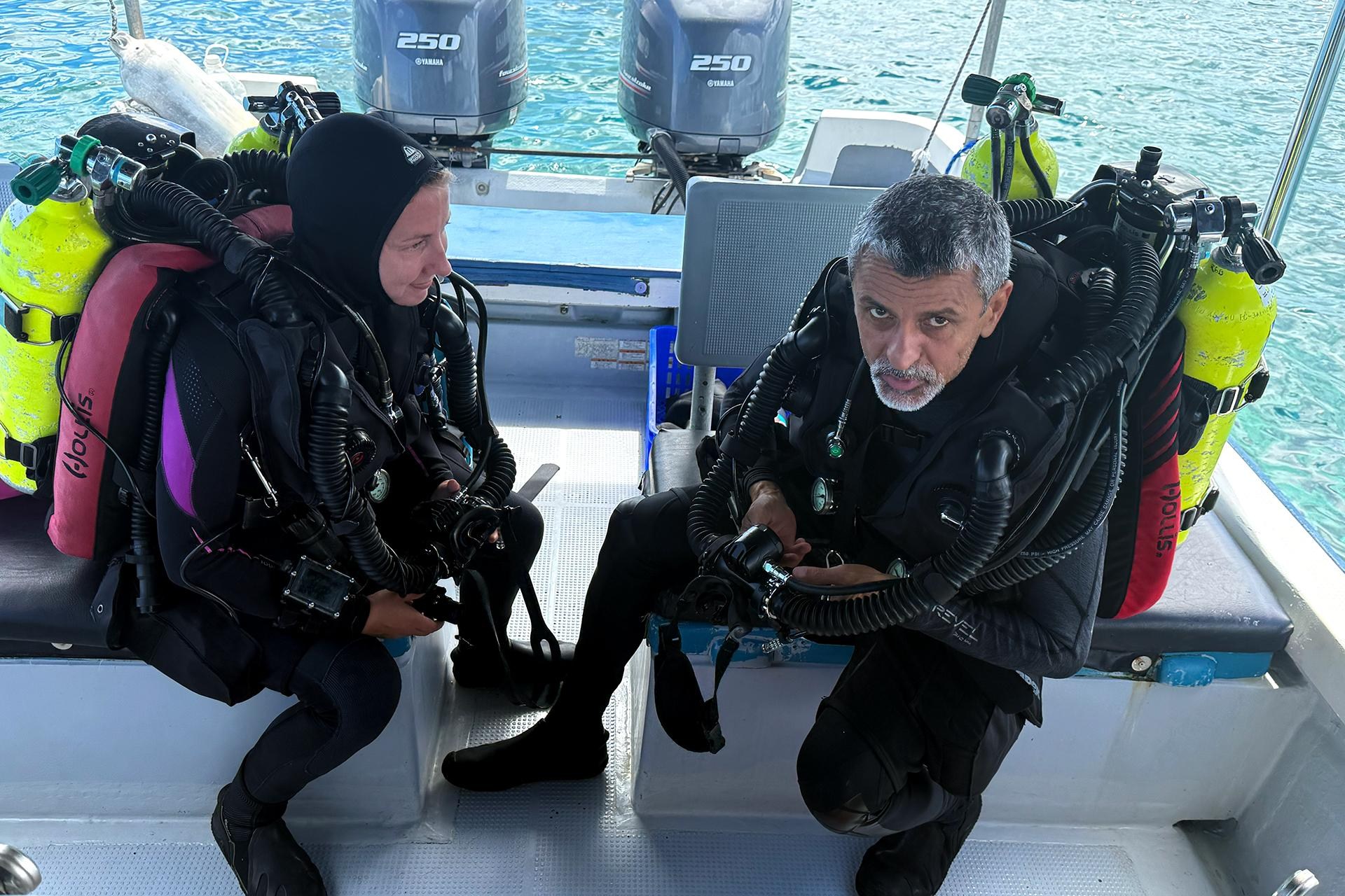 Two people in scuba gear ready to dive into the water