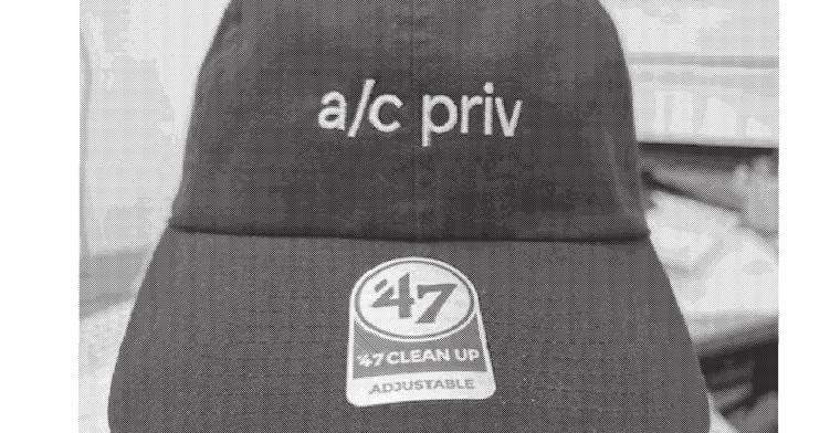 grayscale picture of a baseball cap with a/c priv across the front