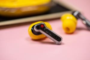 The Nothing Ear 3A earbuds on a mauve background with their case.