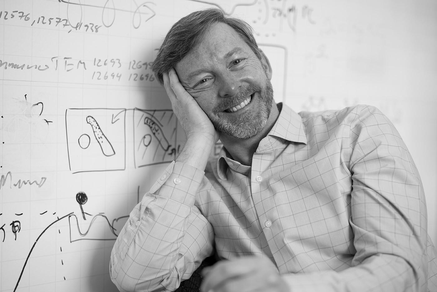bevil conway portrait in grayscale sitting in front of a whiteboard