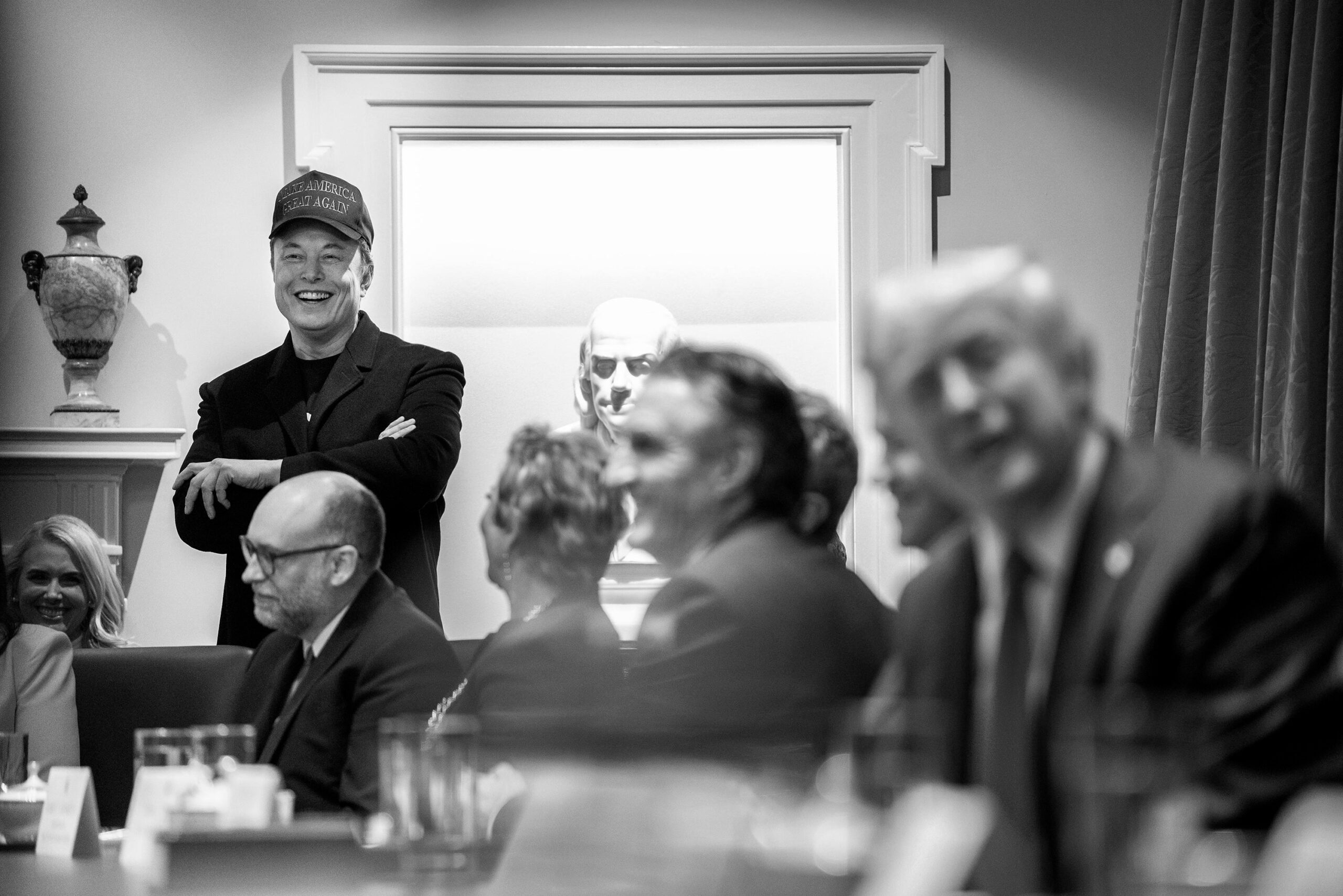 Elon Musk standing in front of a crowded table at a presidential cabinet meeting