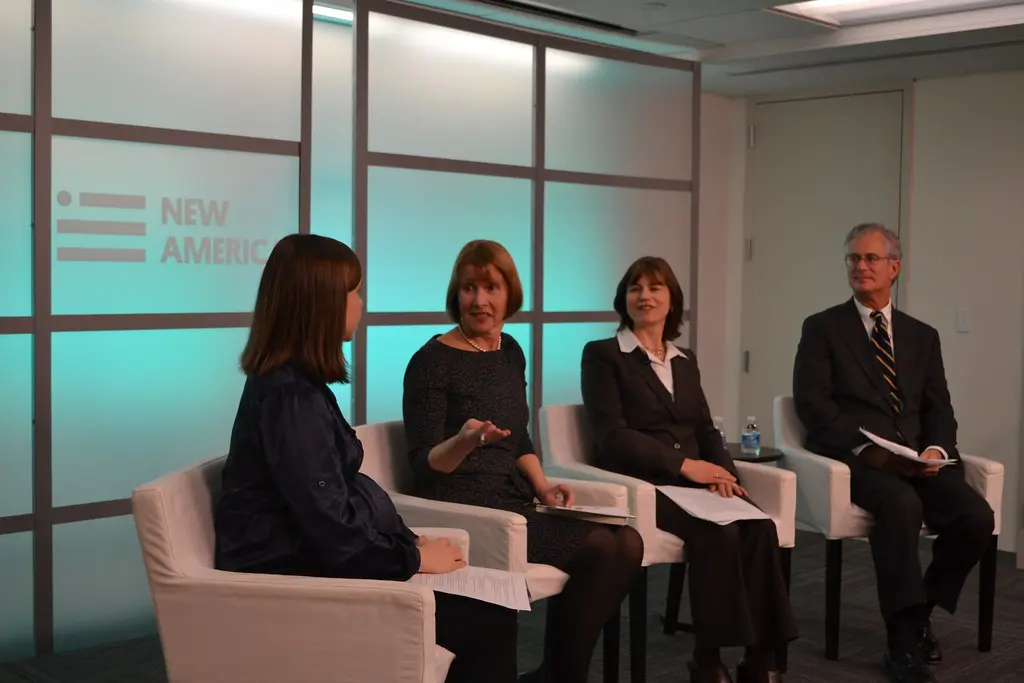 A panel discussion featuring four people seated in white chairs in front of a New America backdrop.