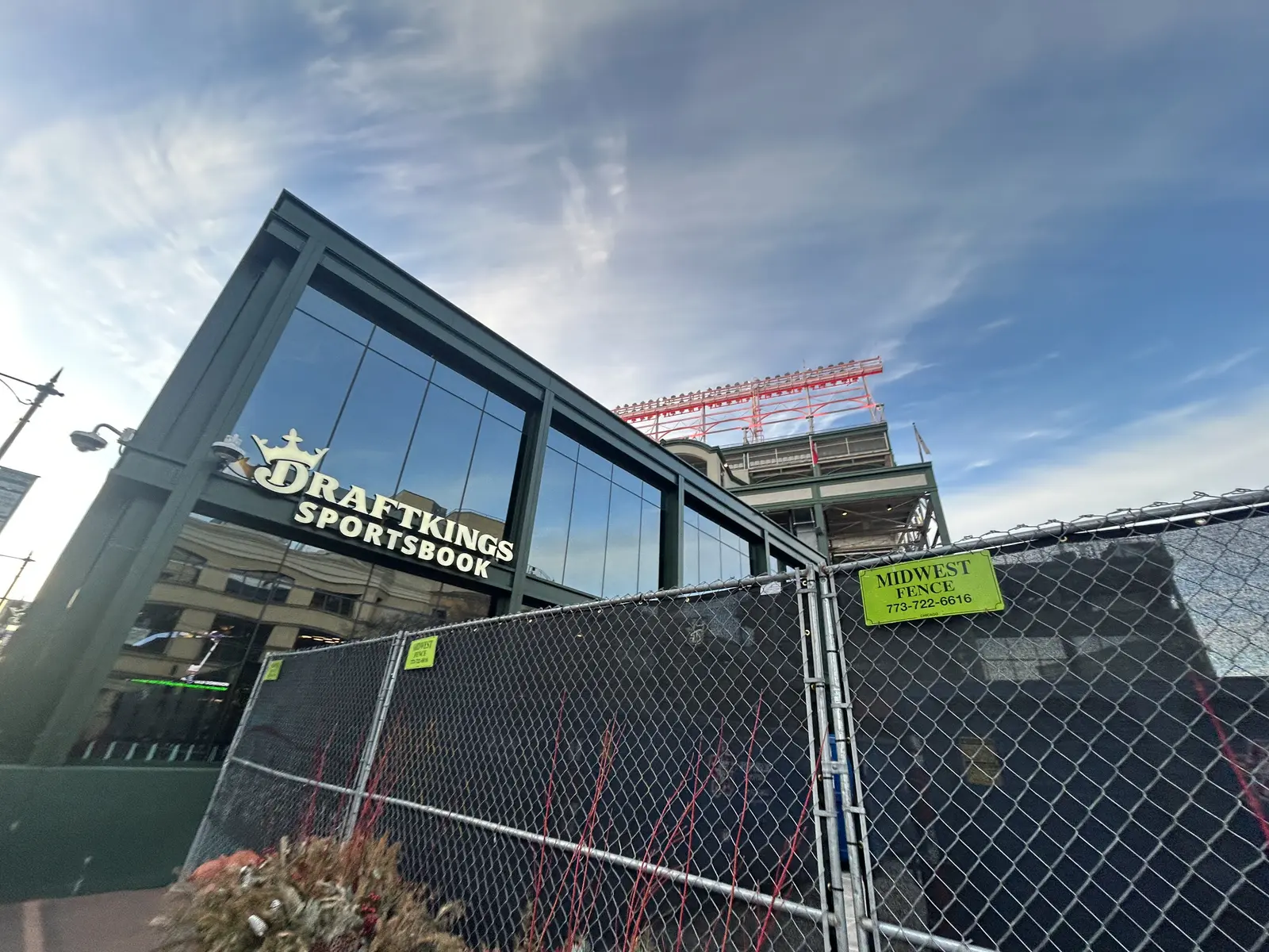 Exterior view of a DraftKings Sportsbook building behind a chain-link fence.