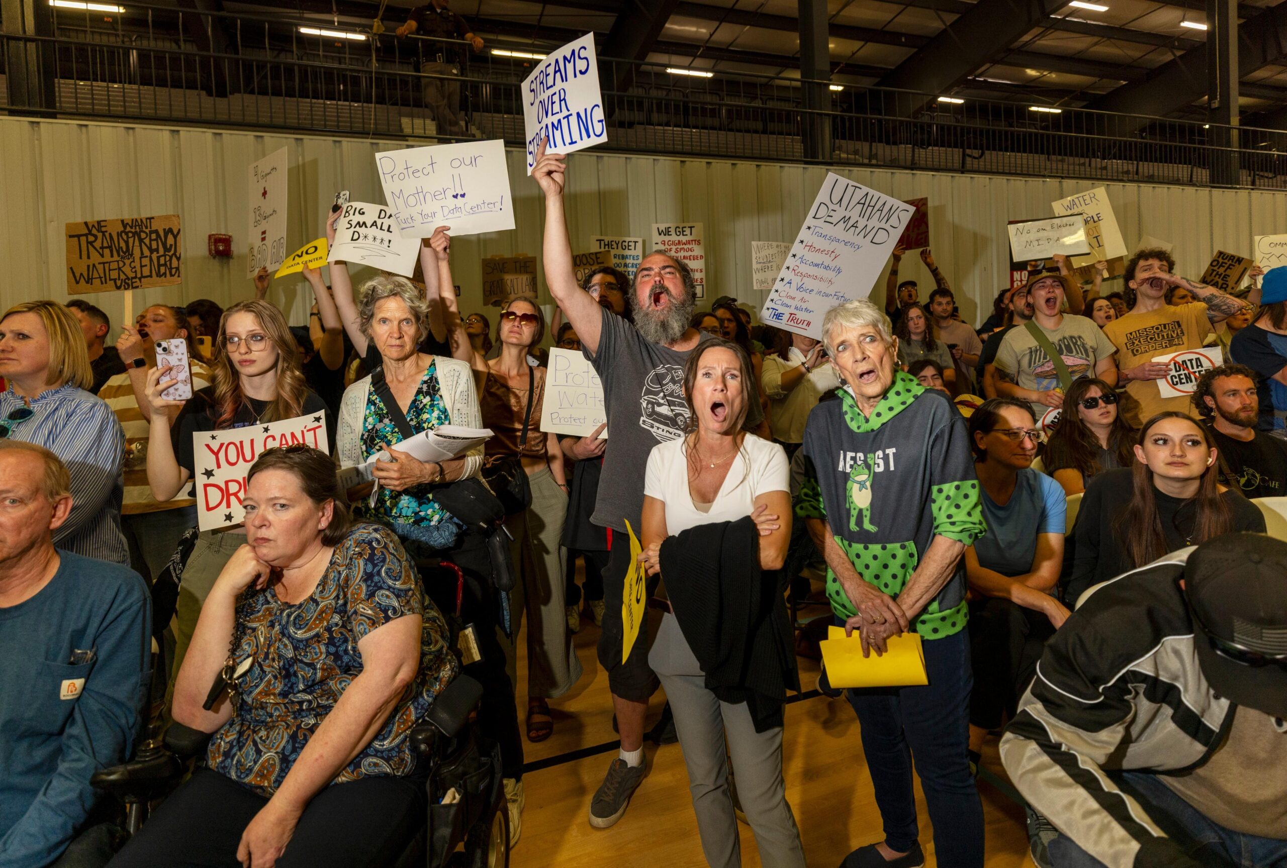 A crowd of people, holding signs, present at the Box Elder County Commission reacting angrily.