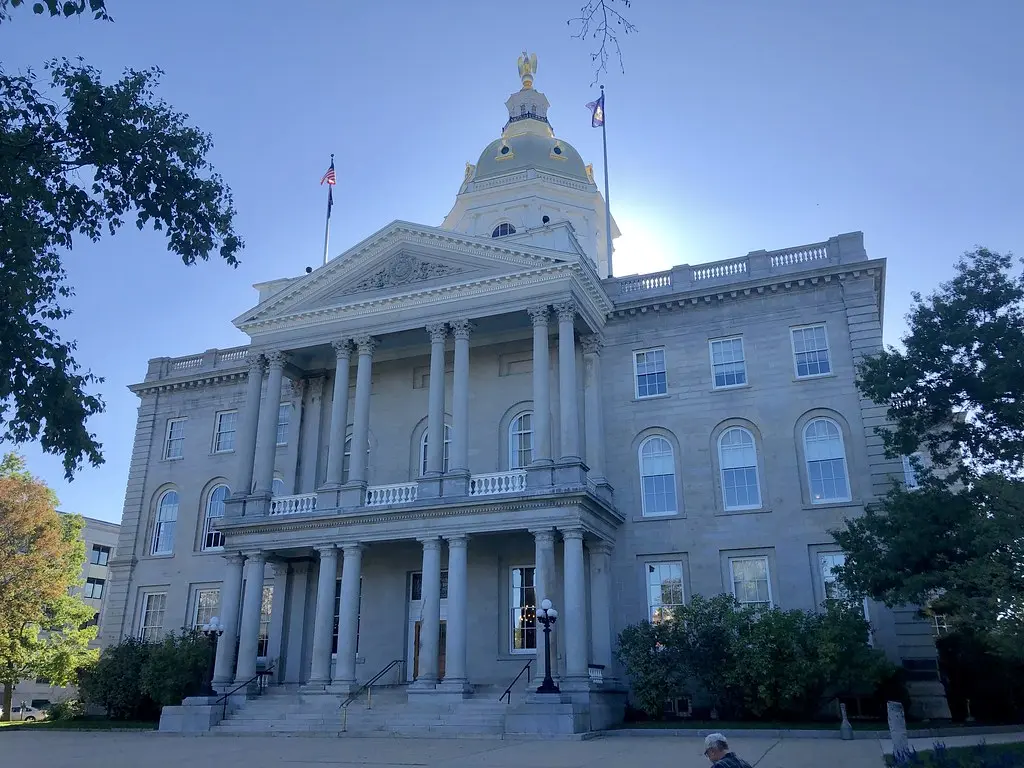 The exterior of the New Hampshire State House in Concord, featuring a golden dome and neoclassical architecture.