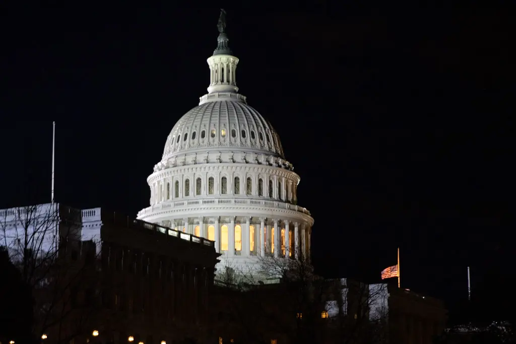The illuminated dome of the United States Capitol building at night.