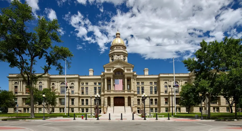 Front exterior view of the Wyoming State Capitol building with its golden dome under a blue sky.